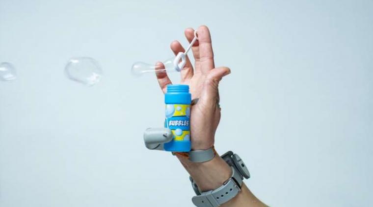 The Third Thumb device being used to blow bubbles single-handedly.