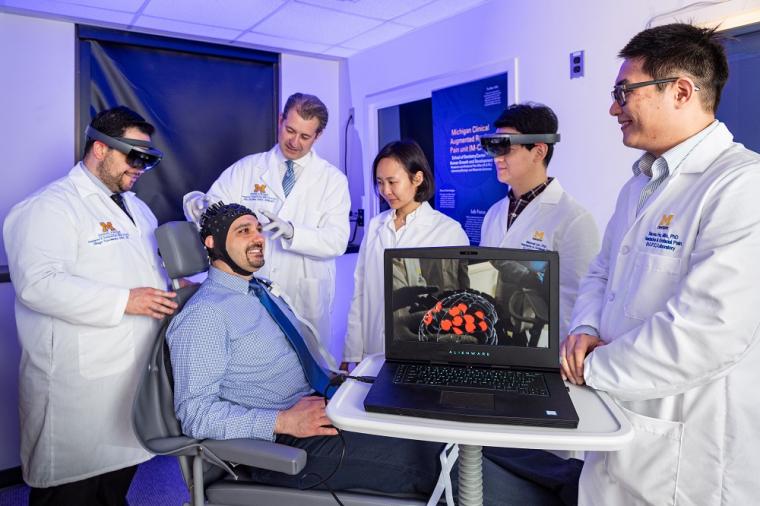 Hassan Jassar (seated) wears a sensor-outfitted cap that detects changes in...