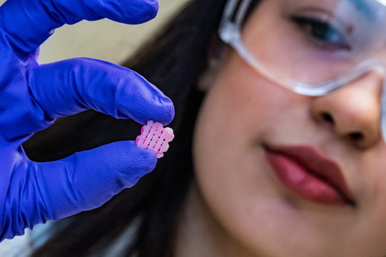 Research scientist Maryam Elizondo holds a 3D printed scaffold engraved with...